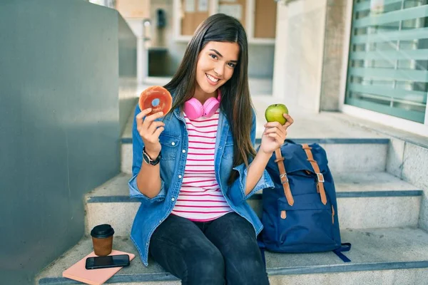 Νεαρή Ισπανίδα Μαθήτρια Χαμογελά Χαρούμενη Κρατώντας Ντόνατ Και Πράσινο Μήλο — Φωτογραφία Αρχείου