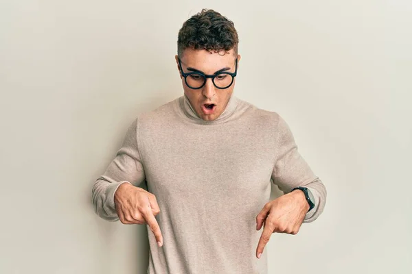 스페인 청년이 무심코 터틀넥 스웨터를 광고를 내면서 손가락을 아래로 향하고 — 스톡 사진