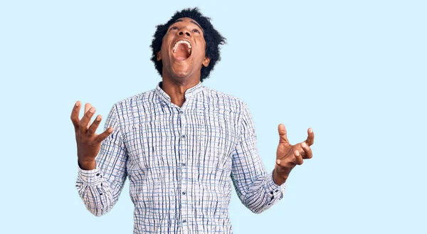 カジュアルな服を着てアフロの髪を持つハンサムなアフリカ系アメリカ人の男性は狂気と怒りの叫びと積極的な表現と腕を上げて叫んでいた フラストレーションコンセプト — ストック写真