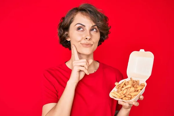 Young Hispanic Woman Holding Potato Chip Serious Face Thinking Question — Stock Photo, Image