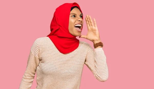 伝統的なイスラム教のヒジャーブスカーフを身に着けている若いアフリカ系アメリカ人女性は大声で叫び 口の上で手で横に叫んでいます コミュニケーションの概念 — ストック写真