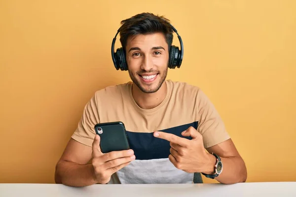 Young Handsome Man Using Smartphone Wearing Headphones Smiling Happy Pointing — Stock Photo, Image