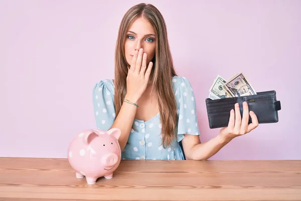 Jong Blond Meisje Met Portemonnee Met Dollars Spaarvarken Zittend Tafel — Stockfoto