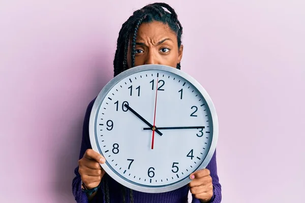 Африканская Американка Косичками Держащая Большие Часы Покрывающие Лицо Скептически Нервно — стоковое фото