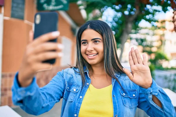 Young latin woman smiling happy doing video call using smartphone at the city.