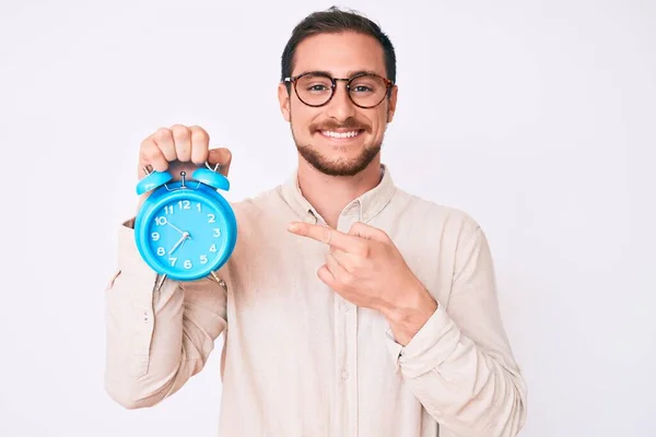 Joven Hombre Guapo Sosteniendo Despertador Sonriendo Feliz Señalando Con Mano — Foto de Stock