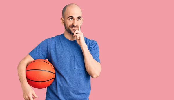 Jovem Homem Bonito Segurando Bola Basquete Rosto Sério Pensando Questão — Fotografia de Stock