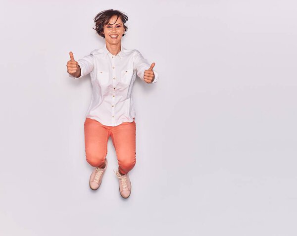 Young beautiful woman wearing casual clothes smiling happy. Jumping with smile on face doig ok sign with thumbs up over isolated white background.