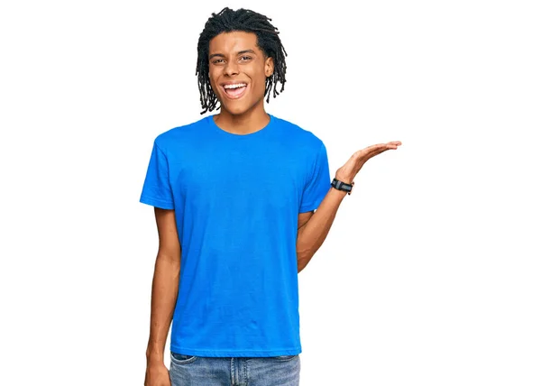 若いアフリカ系アメリカ人男性を着てカジュアルな服を笑顔陽気に提示し カメラを見て手の手のひらで指して — ストック写真