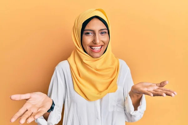 若いですブルネットアラブ女性を身に着けている伝統的なイスラムヒジャーブスカーフ笑顔陽気な提供手援助と受け入れを与える — ストック写真