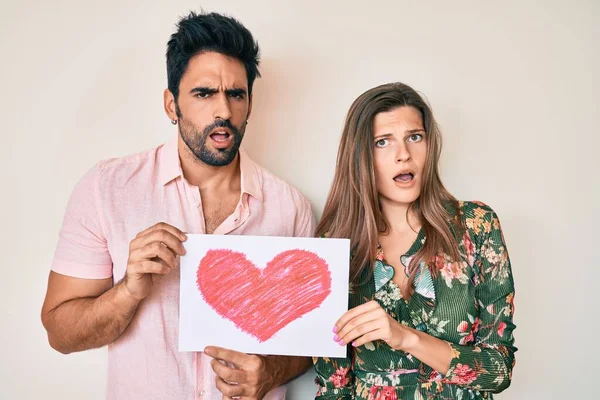 Beautiful Young Couple Together Holding Heart Draw Shock Face Looking — Stock Photo, Image