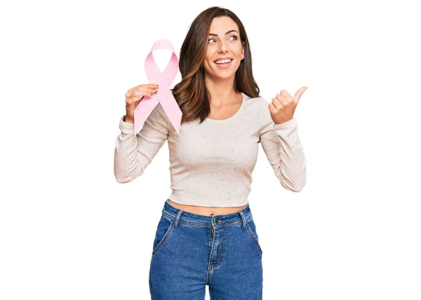 Joven Morena Sosteniendo Cinta Cáncer Rosa Apuntando Pulgar Hacia Lado — Foto de Stock