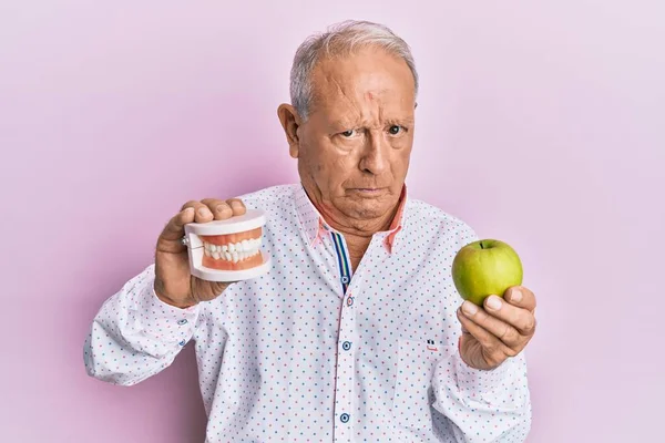 Senior Caucasian Man Holding Denture Green Apple Skeptic Nervous Frowning — Stock Photo, Image