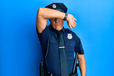 Yakışıklı, olgun, polis üniforması giyen gözleri kollarıyla kapayan, ciddi ve üzgün görünen bir adam. Görme, saklama ve reddetme konsepti 