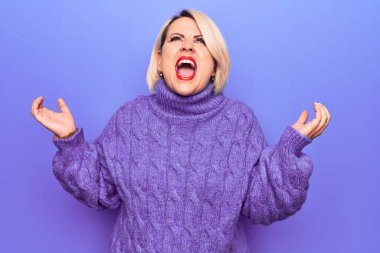 Güzel sarışın ve boyunda bir kadın mor arka plan üzerine balıkçı yaka kazak giyiyor. Deli gibi bağırıyor, agresif bir ifadeyle bağırıyor ve kollarını kaldırıyor. Hayal kırıklığı konsepti.