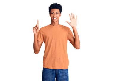 Genç Afro-Amerikalı günlük kıyafetler giymiş altı numarayı gösterip işaret ederken kendinden emin ve mutlu bir şekilde gülümsüyor.. 