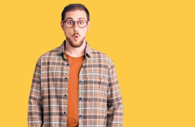 Genç, yakışıklı, günlük kıyafetler giyen, gözlüklü, ağzı açık, korkmuş ve şaşırmış bir beyaz adam. 