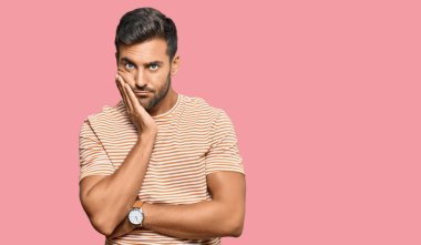 Yakışıklı, günlük kıyafetler giyen, yorgun ve bunalımda kollarını kavuşturmaktan sıkılmış görünen İspanyol bir adam.. 