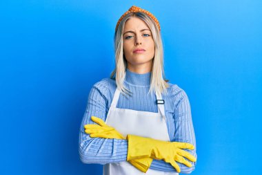 Temiz önlük giyen güzel sarışın kadın ve eldivenler kuşkucu ve gergin, yüzünde çapraz kollu tasvip etmeyen ifade. negatif kişi. 