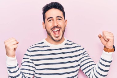 Gündelik kıyafetler giyen genç İspanyol adam gururla bağırıyor, zaferi ve başarıyı kutluyor. Kollarını kaldırarak heyecanla bekliyor. 