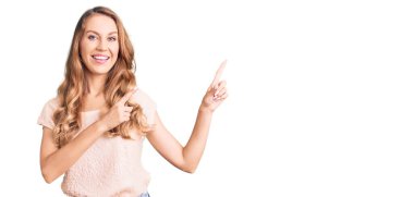 Sarışın, güzel, beyaz bir kadın. Günlük kıyafetler giyiyor. Gülümsüyor ve kameraya bakıyor.. 