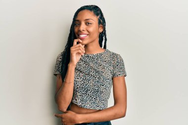 Sıradan kıyafetler giyen Afrikalı Amerikalı kadın kameraya kendinden emin bakıyor kollarını kavuşturmuş ve çenesini kaldırmış bir şekilde gülümsüyor. Olumlu düşünmek. 