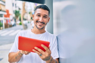 Şehrin duvarına yaslanmış dokunmatik ped kullanan genç bir İspanyol..