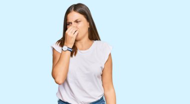 Beyaz günlük tişört giyen genç beyaz kadın pis ve iğrenç bir koku alıyor, dayanılmaz bir koku, nefesini burnunda tutuyor. Kötü kokuyor. 