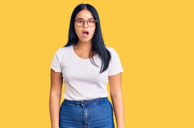 Genç, güzel Asyalı bir kız günlük kıyafetler ve gözlük takıyor. Şaşırmış ve şaşırmış bir ifade, korku ve heyecanlı bir yüz ifadesi var.. 