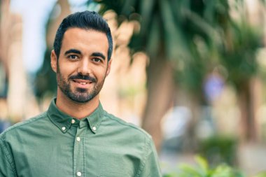 Genç İspanyol adam gülümseyerek şehirde mutlu mesut dikiliyor..