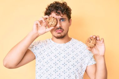 Kurabiye tutan, kıvırcık saçlı, sıkıntılı, sinirli ve korkmuş genç, beyaz bir adam. hüzünlü ifade. 