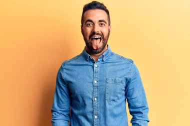 Günlük kıyafetler giyen genç İspanyol adam komik bir ifadeyle dilini dışarı çıkartıyor. duygu kavramı. 