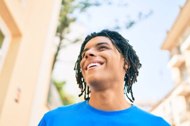 Genç Afrikalı Amerikalı gülümseyen mutlu bir adam şehrin caddesine bakıyor..