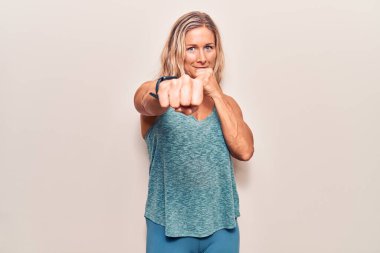 Orta yaşlı beyaz kadın spor kıyafetleri giyiyor. Dövüşmek için yumruk atıyor, agresif ve öfkeli saldırı, tehdit ve şiddet. 