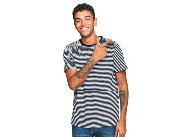 Genç, yakışıklı, Afro-Amerikalı, günlük kıyafetler giymiş, neşeli, yüzünde mutlu ve doğal bir ifadeyle, elleri ve parmaklarıyla yüzünü gösteren bir gülümseme. 