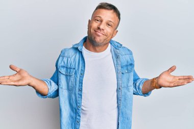 Sıradan bir kot ceket giyen yakışıklı kaslı bir adam. Kolları ve elleri havada, kafası karışmış bir ifade. şüphe kavramı. 