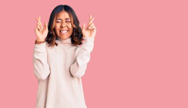 Balıkçı yaka kazak giyen genç, güzel, melez bir kadın. Umut ve gözler kapalı gülümseyerek işaret ediyor. Şans ve batıl inançlar. 