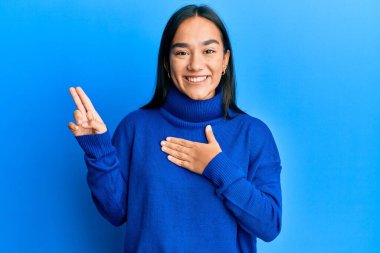 Genç Asyalı kadın, sıradan bir kazak giyip gülümsüyor, el ve göğsü havada küfür ediyor, sadakat yemini ediyor. 