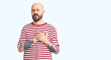 Sıradan kıyafetler giyen, elleri göğsünde, gözleri kapalı gülümseyen ve yüzünde minnet ifadesi olan genç yakışıklı bir adam. sağlık kavramı. 