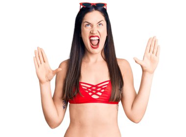 Bikini giyen, deli gibi bağıran, bağıran, saldırgan ifadeler takınıp kollarını kaldıran beyaz bir kadın. hüsran kavramı. 