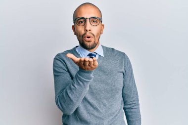 İspanyol yetişkin bir adam gözlük takıyor ve kameraya bakıyor. Elini havaya kaldırarak öpüşüyor. Güzel ve seksi. aşk ifadesi. 