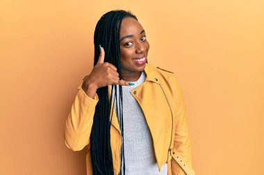 Genç Afro-Amerikalı kadın, sıradan bir ceket giyip gülümsüyor, telefonla el ve parmak hareketleri yapıyor, telefonda konuşuyor gibi. iletişim kavramları. 