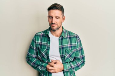 Sakallı yakışıklı bir adam, elleri karnında günlük kıyafetler giyiyor. Çünkü hazımsızlık, acı verici bir hastalık, kendini kötü hissettiriyor. Ağrı kavramı. 