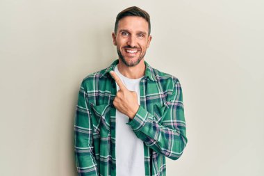 Yakışıklı, sakallı, günlük kıyafetler giyen, neşeli yüzlü, elleri ve parmaklarıyla yüzünü gösteren mutlu ve doğal bir ifade takınan adam. 