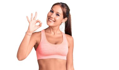 Genç ve güzel İspanyol kadın spor kıyafetleri giyiyor gülümsüyor ve el ve parmaklarıyla 