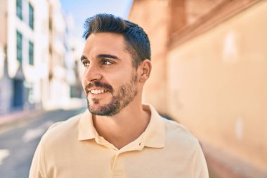 Genç İspanyol adam gülümseyerek şehirde mutlu bir şekilde yürüyor..