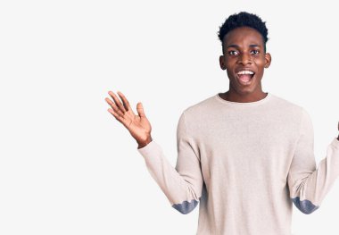 Genç Afro-Amerikan adam gündelik giysiler giyip zaferi mutlu bir gülümsemeyle ve ellerini kaldırarak kutluyor. 