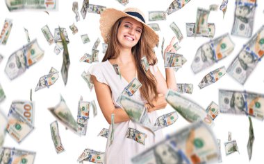 Yazlık elbise giyen, şapkalı, gülümseyen ve kameraya bakan genç ve güzel sarışın bir kadın..