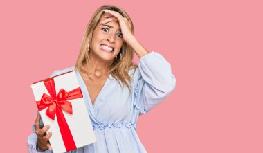 Güzel sarışın kadın, elinde hediyeyle gülümsüyor. Mutluluktan gülümsüyor. 