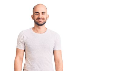 Yüzünde mutlu ve havalı bir gülümseme olan sıradan tişörtler giyen genç yakışıklı bir adam. şanslı kişi. 